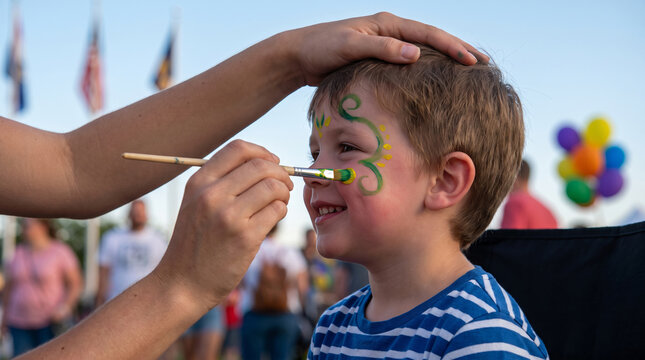 Child getting face painted with green and yellow design at outdoor event