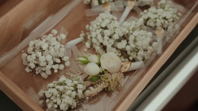 White flower bouquets arranged in transparent boxes on a wooden surface