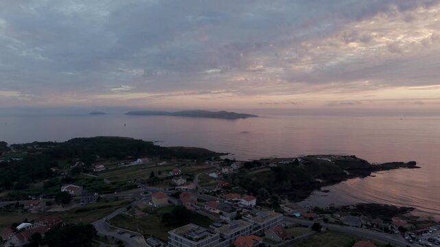 Aerial - Coastal village headland and Atlantic sea with Ons Island at sunset in Galicia Spain