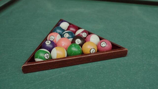 High angle view of colorful pool balls racked in wooden triangle on green table