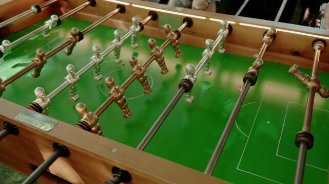 Angle view of classic wooden foosball table with green pitch and metallic players