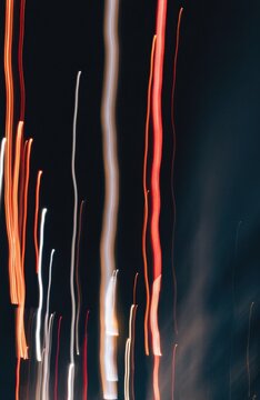 Abstract streaks of orange, white, and red light trails against dark background