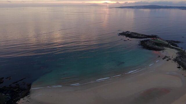 Aerial - Paxos Beach with Turquoise Shallow Water and Rocky Islet at Sunset in Galicia
