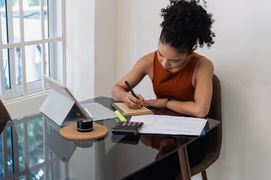 Woman working from home managing finances with tablet and notebook