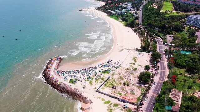 Ong Dia Rock Beach in Phan Thiet, Vietnam. Visitors enjoy the beach activities under the sun. The area is lively with people relaxing and having fun along the shore.