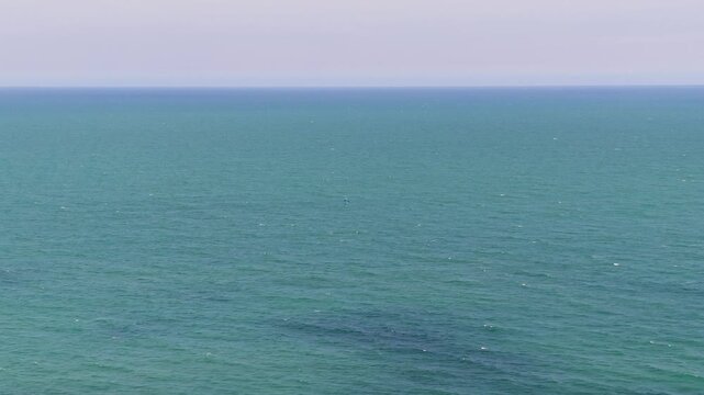 Ong Dia Rock Beach in Phan Thiet, Vietnam shows wide views of the ocean from the shore. The calm water reflects sunlight, making the scene bright and clear.
