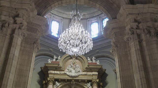 Large Crystal Chandelier Below A Domed Ceiling Above A Carved Altarpiece In A Church
