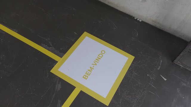 Yellow Bem Vindo welcome marking painted on a scuffed grey concrete industrial floor