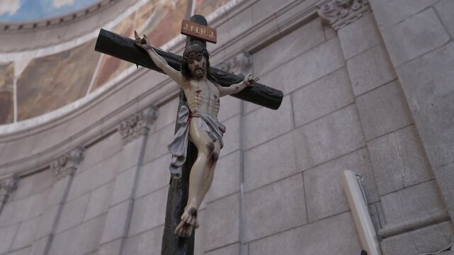 Carved crucifix with Christ figure and INRI plaque against granite wall inside a church