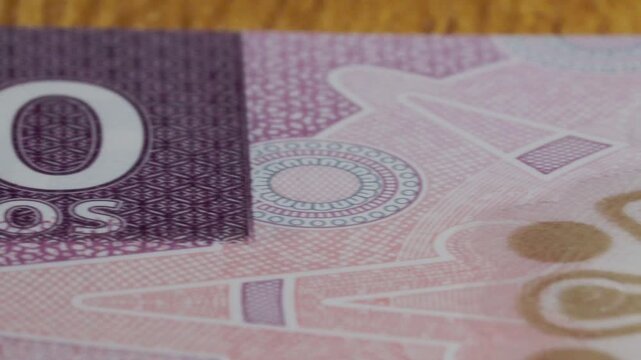 Close-up panning shot moves across Mexican 50 pesos banknote, revealing intricate printed patterns, large denomination numerals, fine details, and security elements.
