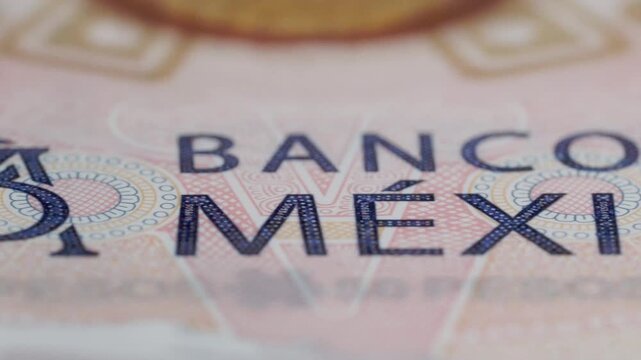 Macro close-up shows Mexican banknote featuring Banco de Mexico text, intricate geometric patterns, fine printed details, colorful security elements, and detailed currency design.