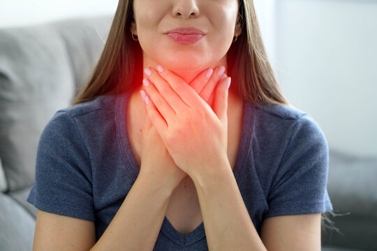 Young woman with hands on neck suffering from sore throat or inflamed tonsils