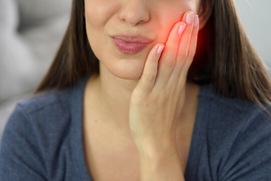 Close up detail of unidentified young woman suffering from toothache with painful face expression