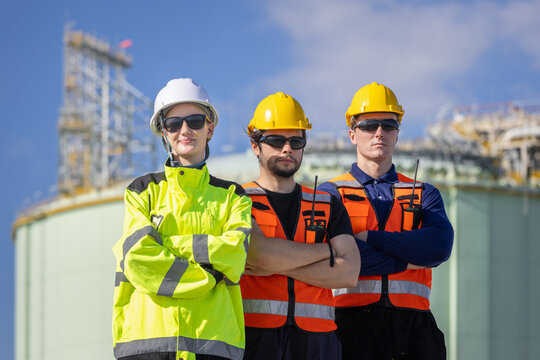 LNG plant engineers team standing with arms crossed at industrial facility, Liquefied natural gas workers in safety gear posing at energy terminal, Technicains team at natural gas storage facility
