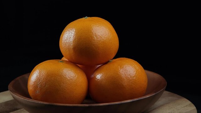 Orange fruit in basket on wooden table with black background