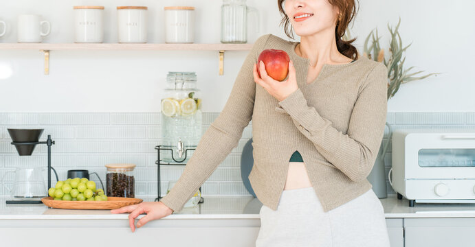 A woman eating an apple in the kitchen (diet, vegetarian)