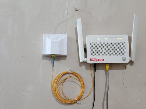 IndiHome Fiber Optic ONT Modem and Optical Terminal Box on Wall with green indicator lights