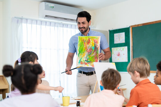 Caucasian male teacher teaching art lesson to children in classroom.
