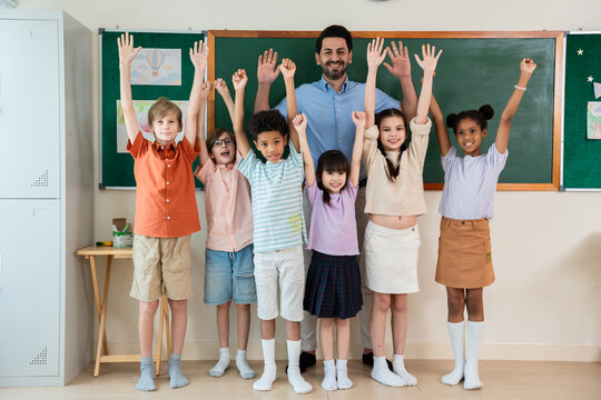 Portrait of diversity student standing with male teacher at primary school. 