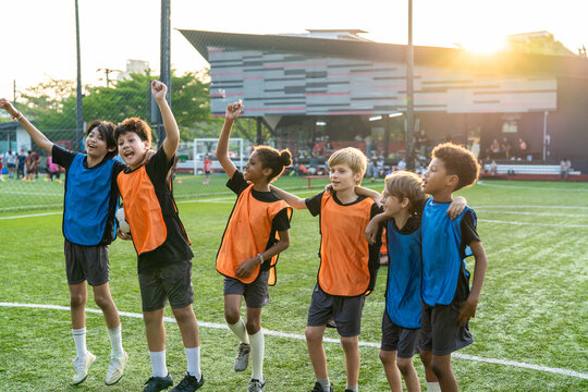 Group of diverse child football players celebrating victory together. 