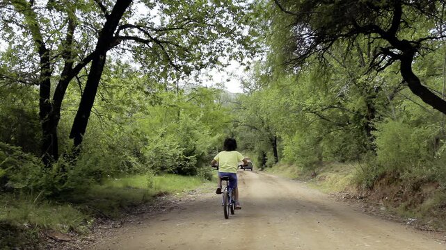 Young Cyclist Riding Through Tree-Canopied Rural Road in Argentina - 4K