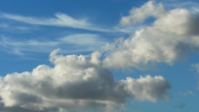 White clouds time lapse. Clouds running across the blue sky. 4k Timelapse of white clouds with blue sky background. Weather concept b roll shot.