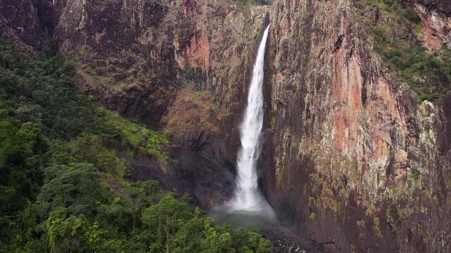 Cinematic aerial view of Wallaman Falls plunging down steep rocky cliffs in tropical Queensland Australia.