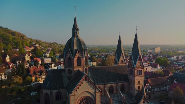 Aerial pan from right to left showcasing the side profile of St. Peter's Cathedral in Heppenheim at golden sunset, Germany