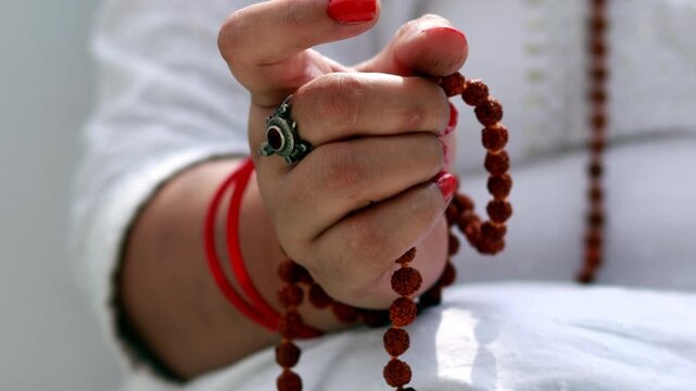 Female hand holding rudrakasha prayer beads in hands.