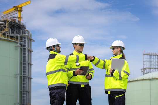 lng plant engineer team fist bumping for success at terminal, liquefied natural gas workers celebrating teamwork at industrial facility, energy industry professionals showing unity and success outdoor
