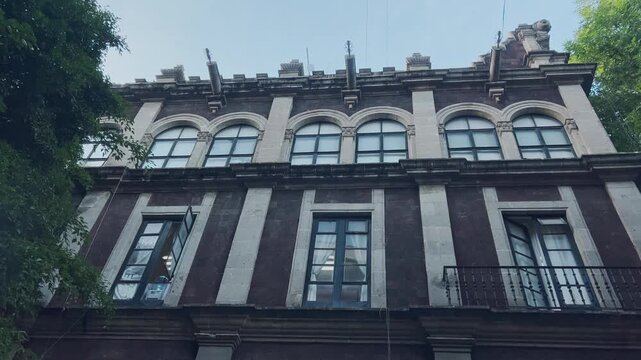 Historic ornate building facade with arched windows, balconies, decorative details and dark stone columns in Cuernavaca, Mexico, showcasing distinctive historic architecture