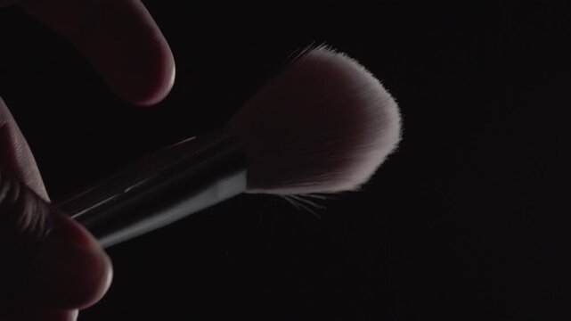 Close up of soft makeup brush bristles against dark background showing rounded brush heads fine texture and detailed cosmetic application surface