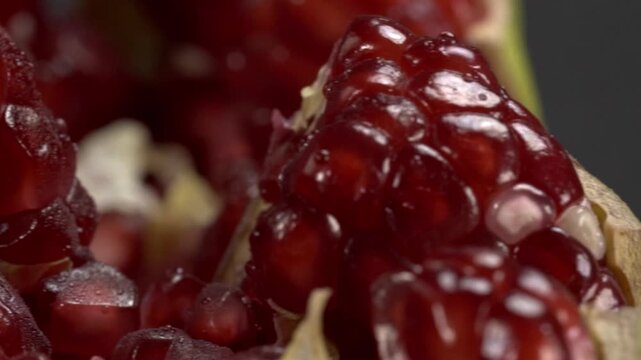 Macro view of glossy red pomegranate seeds clustered inside fresh fruit showing detailed texture juicy arils and natural color