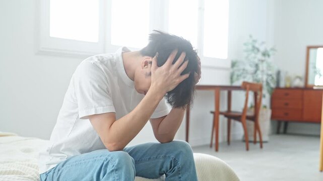 寝室で悩む男性。疲労、肩こり、つらい、落ち込む、失敗、困る、ストレス、がっかり、不満、ホテル、宿泊