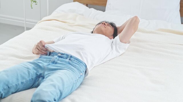 ベッドに寝る男性。疲れ、疲労、昼寝、ライフスタイル、寝室、落ち込む、あくび、寝不足、不眠症、眠る