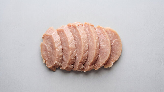 Sliced raw pork loin on light grey background