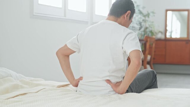 腰痛に悩むシニア男性。ぎっくり腰、ミドル、中高年、老化、加齢、痛み、困る、ヘルニア、ベッド、健康