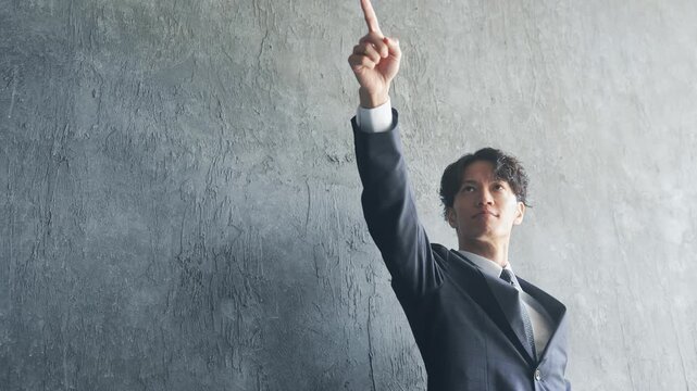 上を指さす若い男性ビジネスパーソン