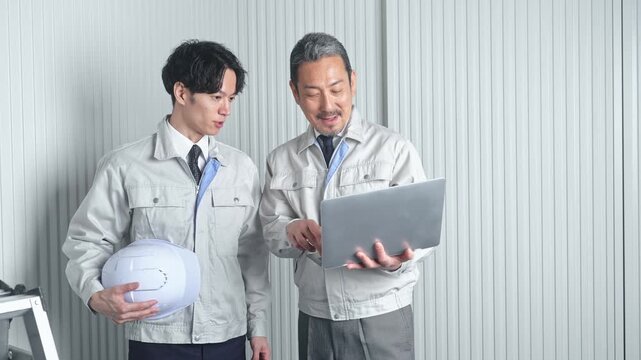 打ち合わせする男性作業員のグループ。建設、工事、工場、業者、相談、会議、DX、修理、点検、建築、内装