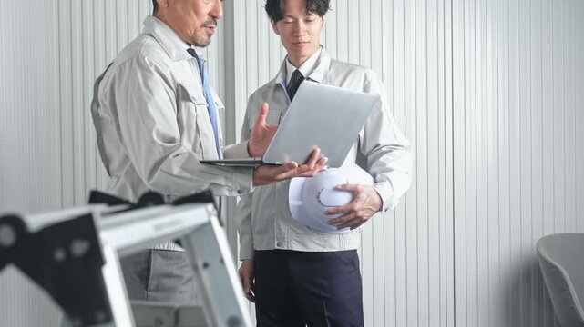 打ち合わせする男性作業員のグループ。建設、工事、工場、業者、相談、会議、DX、修理、点検、建築、内装