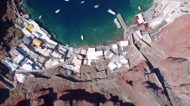 Aerial view of oia ammoudi port in santorini greece showing turquoise waters and volcanic caldera cliffs.