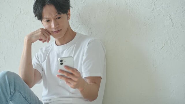 スマホを使う男性。アプリ、SNS、動画、メール、DX、ゲーム、リラックス、若者、検索、スマートフォン