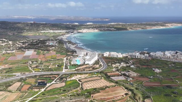 mellieha bay sweeping sandy beach turquoise water resort hotel pool complex malta coastline aerial drone footage marfa ridge horizon farmland countryside rural fields north malta panorama