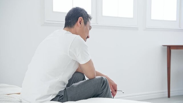 肩こりに悩むシニア男性。疲労、疲れ、ベッド、ミドル、中高年、ストレス、加齢、老化、落ち込む、がっかり