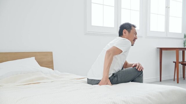 腰痛に悩むシニア男性。ぎっくり腰、ミドル、中高年、老化、加齢、痛み、困る、ヘルニア、ベッド、健康