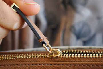 Hand pulling zipper on a brown bag © Towfiqu Barbhuiya 