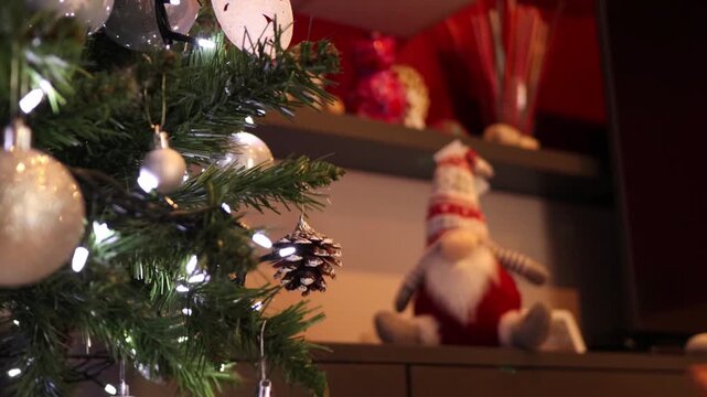 Man hands hanging pinecone decoration on green christmas tree branches for holiday celebration.