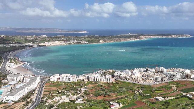 mellieha bay sandy beach turquoise mediterranean coastline resort hotels marfa peninsula malta aerial drone footage coastal town crescent bay swimming pools waterfront development scenic panorama