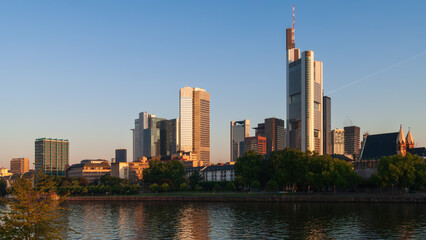Fototapeta premium FRANKFURT, GERMANY - JULY 15, 2007: Financial district skyline with Commerzbank Tower and skyscrapers illuminated by golden morning light across the Main river.