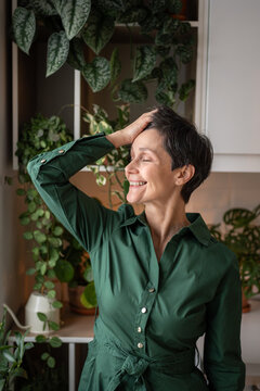 Satisfied happy mature woman enjoying morning in cozy home kitchen during weekends. Glad graceful female slow living, new short hairstyle, happy relaxed weekend with yourself on retirement. 